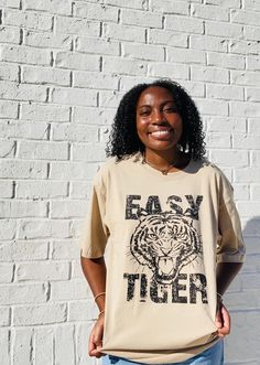 Stay on-trend with the Easy Tiger Oversized Graphic Tee. This tan-colored shirt is designed with a slightly oversized fit, providing both comfort and style. Perfect for any casual occasion, this tee is a must-have for any fashion-forward individual. Trendy Khaki Crew Neck T-shirt, Oversized Brown T-shirt For Everyday, Trendy Beige T-shirt For Streetwear, Trendy Beige Streetwear T-shirt, Trendy Oversized T-shirt For Everyday, Trendy Beige Relaxed Fit T-shirt, Spring Oversized Beige T-shirt, Trendy Beige Tops With Graphic Print, Oversized Brown T-shirt For Fall