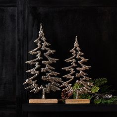 two silver christmas trees sitting on top of a table