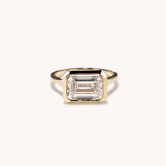 a gold ring with an emerald cut diamond