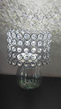 a clear glass vase sitting on top of a table next to a white wall and window