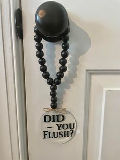 a door with a sign that says did you flush? on it and a ball hanging from the handle