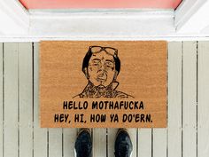 a person standing in front of a door mat that says hello mothhafuka hey, hi, how ya down