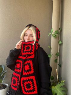 a woman wearing a red and black crocheted scarf