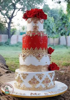 a three tiered wedding cake with red roses on top and gold trimmings