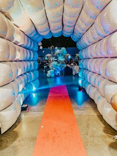 an orange carpet is on the floor in front of white balloons with blue and pink lights