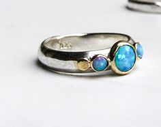 Recycled Silver and 14k Gold With blue Opal ring (The listing is only for the ring with the blue stone) If you want it with the secend ring: https://www.etsy.com/il-en/listing/514681991/white-topaz-ring-wedding-bands-stackable?ref=shop_home_active_176&pro=1 You are looking at a beautiful HAND MADE silver and 14k gold ring with lovely blue opal. The opal stone is setting in 14k gold bazel. It is impressive, powerful and very beautiful ring. Size blue opal is 6mm And the small opal are 3 mm Cu Unique Blue Multi-stone Opal Ring, One Of A Kind Blue Sterling Silver Rings, Opal Ring Silver, Blue Opal Ring, Jewelry Opal, White Topaz Rings, Bridal Ring Sets, Handmade Rings, Recycled Silver