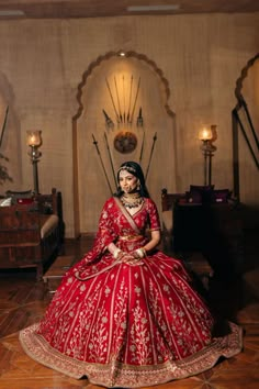 a woman in a red and gold bridal gown sitting on the floor with her hands behind her back