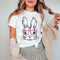 Hop into spring with our "Bunny With Glasses" Bella Tee! Featuring a playful design of a bunny wearing glasses, this easter tee is sure to make you stand out. Made from comfortable fabric, this tee is perfect for any Easter celebration. (Don't be shy, show your bunny swagger! Spring Cartoon Print T-shirt, Funny Pink T-shirt For Spring, Casual T-shirt With Bunny Design And Crew Neck, Casual Crew Neck T-shirt With Bunny Design, Playful Cartoon Print T-shirt For Spring, Casual Cotton T-shirt With Bunny Print, Spring Bunny Print Short Sleeve Tops, Spring Crew Neck Tops With Bunny Design, Spring Bunny Print Tops With Short Sleeves