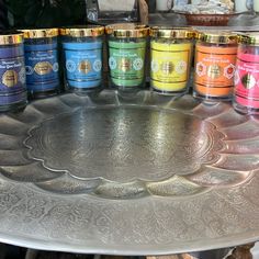 many different types of candles are on a silver platter in front of other items