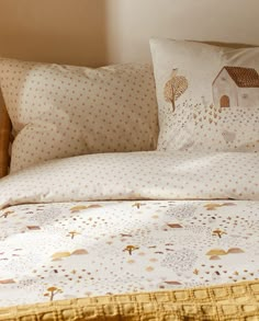 a bed with white and gold sheets and pillows