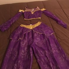 a purple and gold dress laying on top of a bed