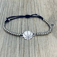 a bracelet with a basketball on it sitting on top of a wooden table next to a string