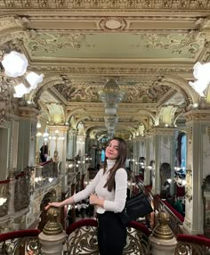 a woman standing in front of a chandelier with her hand on her hip