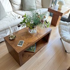 a living room filled with furniture and a wooden table next to a white couch on top of a hard wood floor