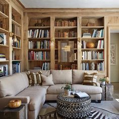 a living room filled with lots of bookshelves next to a couch and ottoman