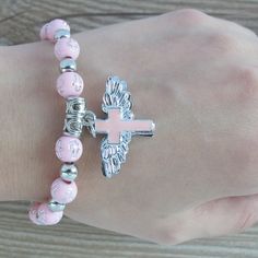 "12 PCS Wing of Angel gold or silver bracelets are absolutely stunning Favors for baptism, Christening, and any religious event. 12 Pcs PINK ANGEL CHARM BRACELET - A meaningful and useful favor for Baptism and religious events The Wings of angel adorn with beautiful enamel cross Stretchy bracelet fits youth and adult wrists. Wood bead size 8mm, Charm size: .75\" x 1\", fits youth & adult" Personalized Pink Spiritual Bracelet, Personalized Pink Spiritual Bracelets, Spiritual Personalized Pink Bracelets, Spiritual Personalized Pink Bracelet, Spiritual Pink Personalized Bracelets, Personalized Pink Spiritual Charm Bracelet, Adjustable Pink Cross-shaped Jewelry, Spiritual Pink Beaded Hypoallergenic Bracelets, Personalized Pink Rosary Bracelet For Baptism