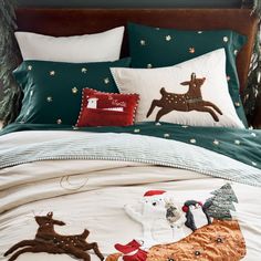 a bed with christmas decorations on it and pillows in the shape of deers, snowmen