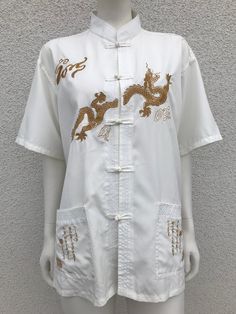 White/cream men's shirt embroidered with dragon patterns. The shirt has two side pockets with oriental patterns, a mandarin collar and a full-length frog fastening. Material: 80 % polyester, 20 % cotton. Size: The size on the label is 41,  it's best suited to men's sizes XL - X Large. Also check out the measurements below: Shoulder: 51 cm - 20.07 inches Armpit to armpit 58.5 cm - 23.03 inches Total length 72.5 cm - 28.54 inches Sleeve length from shoulder: 22.5 cm - 8.85" CONDITION: Very good vi Chinese Shirt Men, Chinese Collar Mens Shirt, Chinese Vintage Shirt, Chinese Shirt, Embroidered Dragon, Cotton Dragon Print T-shirt For Streetwear, Chinese Mandarin, Dragon Pattern, Mandarin Collar