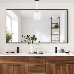 a bathroom with a large mirror above the sink and wooden cabinetry on the side