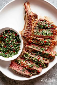 grilled steak with pesto sauce on a white plate next to a small bowl