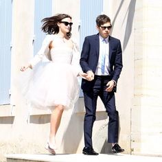 a man and woman dressed in formal wear walking down the street together, with sunglasses on their heads