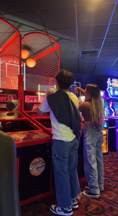 two people standing next to each other at a pinball game machine in a casino