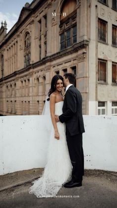 a bride and groom standing in front of an old building