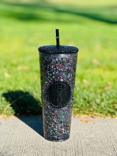 a starbucks cup sitting on the ground with sprinkles and a straw in it