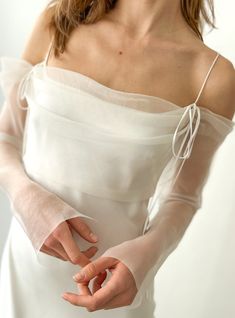 a woman in a white dress holding her hands together