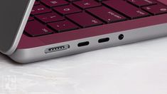 an open laptop computer sitting on top of a white table next to a red and black keyboard