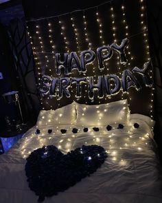 a bed with white sheets and lights in the shape of a heart on top of it