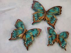 three blue butterflies sitting on top of a white cloth covered table next to each other