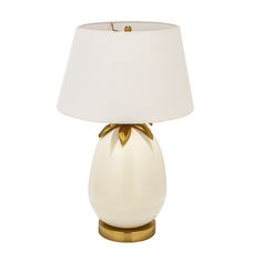 a white table lamp with a gold base and a white lampshade on top