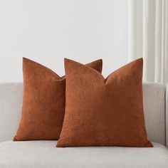 two brown pillows sitting on top of a white couch