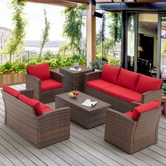 an outdoor living area with red cushions and wicker furniture on a wooden deck overlooking the water