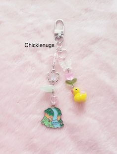 a key chain with a cartoon character and rubber ducky on it, sitting on a pink fuzzy surface