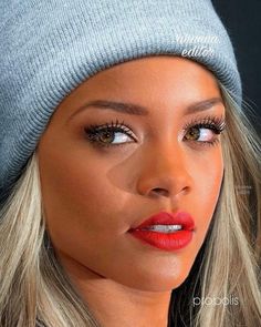 a woman with long blonde hair wearing a beanie and red lipstick on her lips