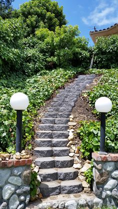 a set of stone steps leading up to the top of a hill surrounded by greenery