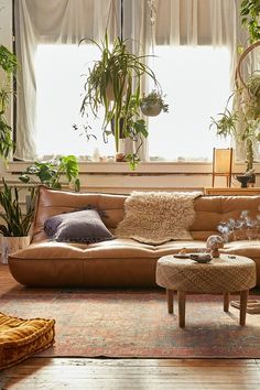 a living room filled with lots of furniture and plants in the window sills