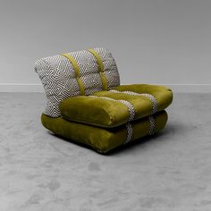 a green chair sitting on top of a cement floor next to a white and black pillow