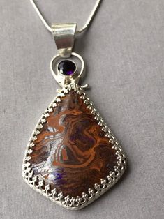 "This is a stunning opal pendant with a purple hue in it. Enhanced with a deep purple 6mm amethyst. Set in a gallery bezel of sterling silver. The opal is approximately 40 x 30 mm. Overall including the bail approximately 2-1/2 x 1-1/4\". Comes with a complementary sterling silver chain, or add your favorite chain. Op211" Purple Opal Gemstone Jewelry, Purple Cabochon Pendant Jewelry, Unique Purple Cabochon Jewelry, Purple Cabochon Gemstones For Gift, One Of A Kind Purple Pendant Jewelry, One-of-a-kind Purple Pendant Jewelry, Unique Purple Sterling Silver Gemstones, Silversmithing Jewelry, Boulder Opal Ring