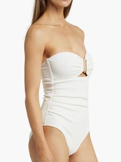 BACK IN STOCK! A timeless summer staple, the best-selling Lisa One Piece bandeau swimsuit features a sweetheart neckline, an elevated gold hammered U-ring trim and a sexy and subtle peekaboo. Hidden boning at the bust provides additional support, and slight ruching smooths and shapes your figure into an hourglass shape. Style yours with a pareo and sandals for lunch by the pool. DETAILS Color: Ivory Texture Fabric: 88% Recycled Nylon 12% Spandex Eco Textured Swim Certified UPF 50+ to block 99% o Elegant Strapless Swimwear For Pool, Elegant Strapless Swimwear For Summer, Sleeveless Seamless One-piece For Poolside, Elegant Fitted Cream Swimwear, Cream Fitted Sleeveless Swimwear, Chic White Strapless Swimwear, Elegant White Bandeau Swimwear, Cream One-piece Swimwear For Summer, One-piece Textured Swimwear For Poolside