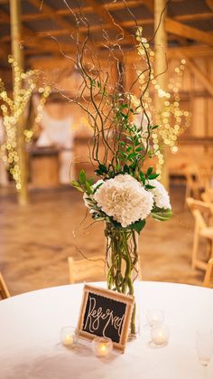 an arrangement of flowers and greenery in a vase on a table