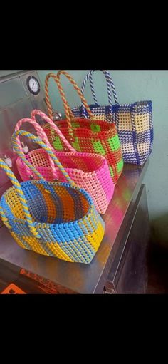 four woven bags sitting on top of a metal table next to a clock and wall