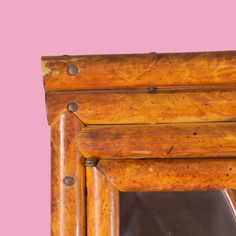 an old wooden frame with metal rivets on the bottom and sides, against a pink background