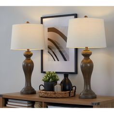 two lamps sitting on top of a wooden table next to a basket with plants in it