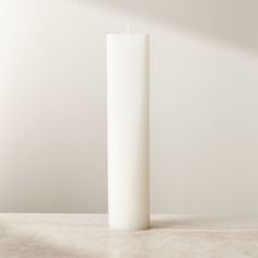 a tall white candle sitting on top of a table