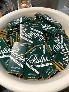 a white bowl filled with green and gold bar wrappers sitting on top of a counter