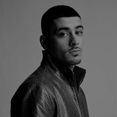 a black and white photo of a man in a leather jacket looking at the camera