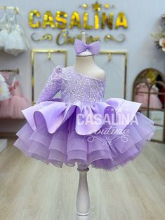 Watch your daughter light up with joy as she steps into the enchanting world of the Malinda Dress in Lilac Purple. This mesmerizing garment is tailor-made for baby girls who deserve to revel in elegance and charm. The Malinda Dress, with its graceful long train, promises to transform your little one into a fairy-tale princess with every wear. In a delightful shade of Lilac Purple, this knee-length dress features a voluminous skirt, creating a playful and spirited silhouette. The upper bodice of Princess Style Lavender Party Gown, Princess Style Lavender Gown For Party, Princess Lavender Gown For Party, Purple Fitted Dress For Pageant, Form-fitting Purple Dress For Pageant, Fitted Purple Dress For Pageant, Lavender Ruffled Dress For Wedding, Purple Princess Dress For Baptism In Spring, Lavender Fitted Princess Dress For Dress-up